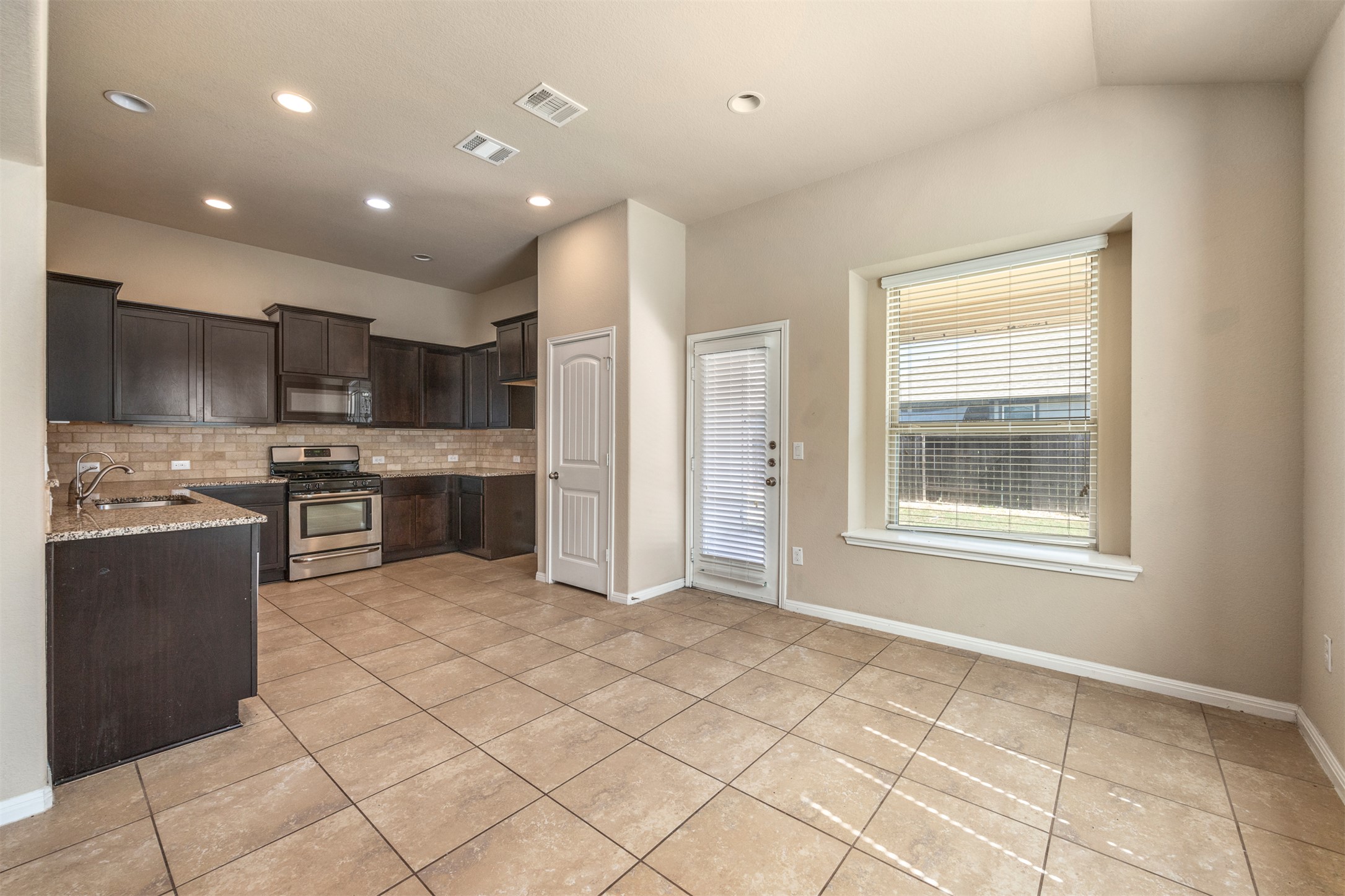 125 Serrano Street Georgetown, TX 78628 - Photo 2 of 18 a kitchen with stainless steel appliances granite countertop a refrigerator and a stove top oven