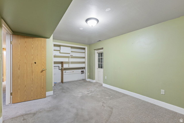 875 Cedar Hollow Road Lehi, UT 84043 - Photo 50 of 76 Light green walls with white trim, built-in shelving, carpet flooring, and a white paneled door with glass inserts