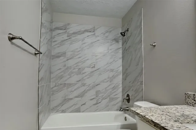 a bathroom with a granite countertop sink and a bathtub