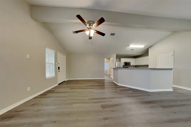 a view of empty room with wooden floor and window