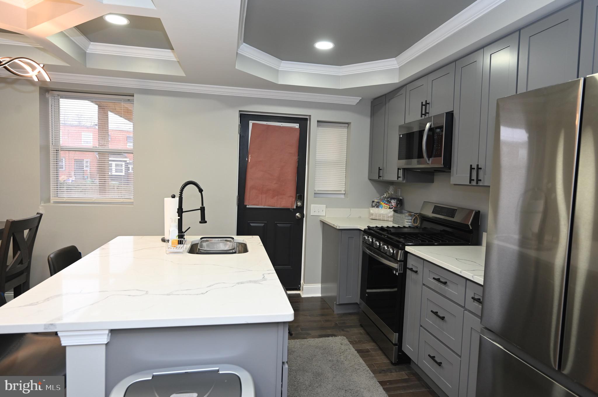 4139 Mountwood Road Baltimore, MD 21229 - Photo 40 of 53 a kitchen with stainless steel appliances kitchen island granite countertop a refrigerator a sink dishwasher a stove with wooden cabinets and floor