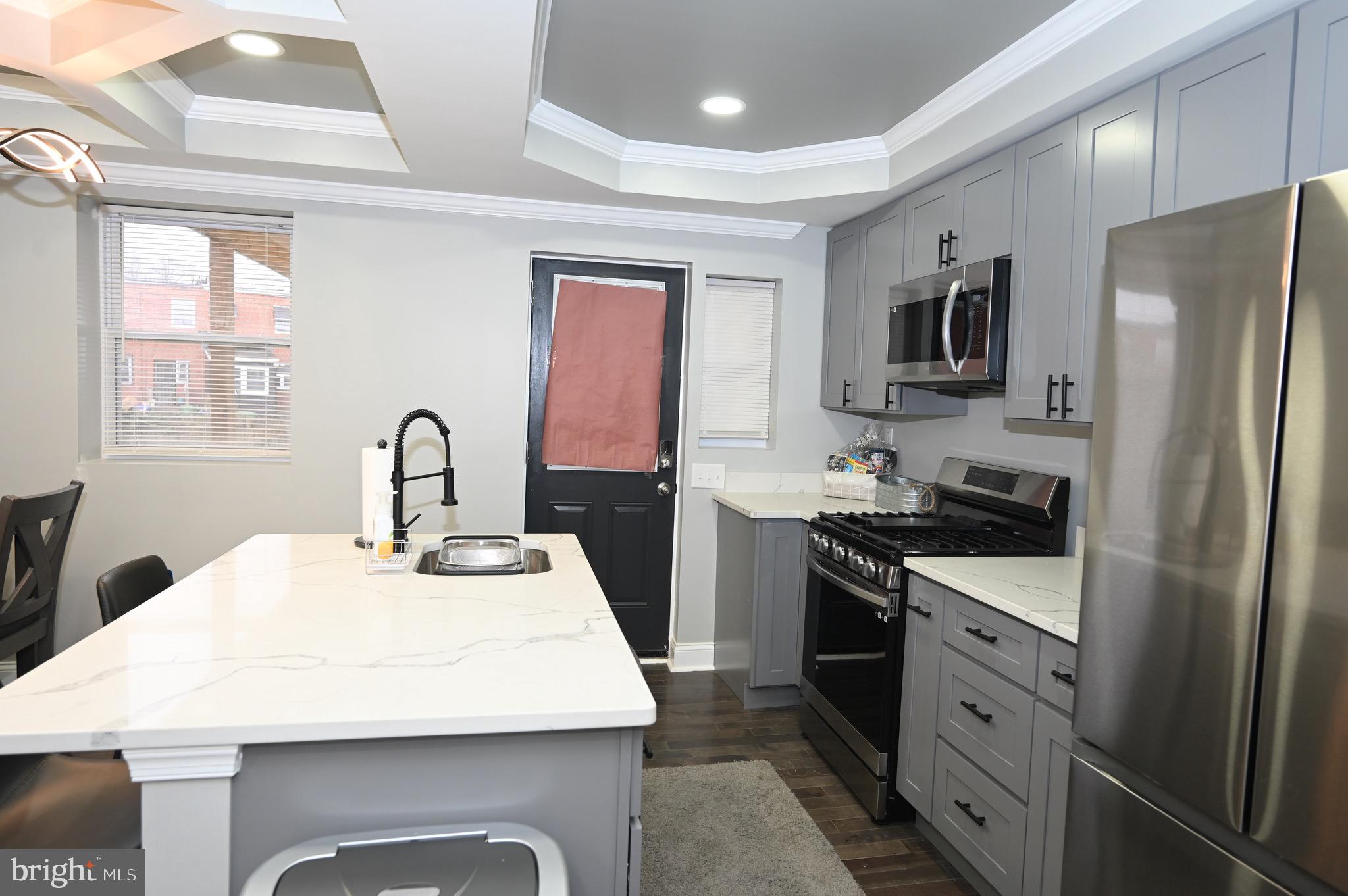 4139 Mountwood Road Baltimore, MD 21229 - Photo 41 of 53 a kitchen with stainless steel appliances kitchen island a table chairs in it and white cabinets