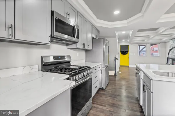 a kitchen with stainless steel appliances granite countertop a sink a stove top oven a chimney wooden cabinets and floors