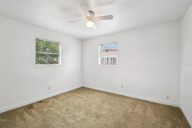 an empty room with a window and a ceiling fan