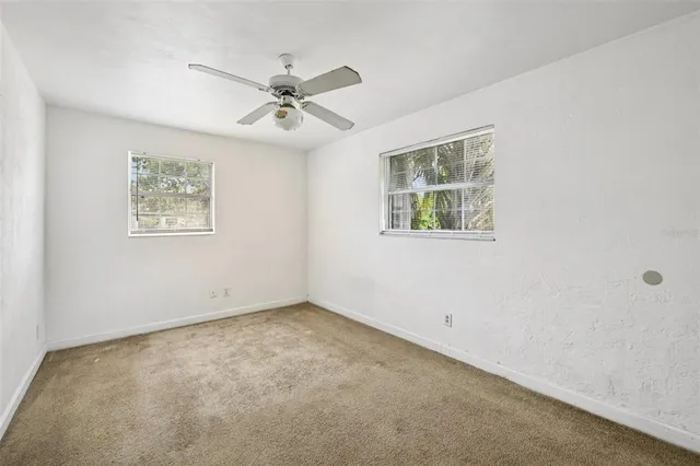 an empty room with a window and a fan