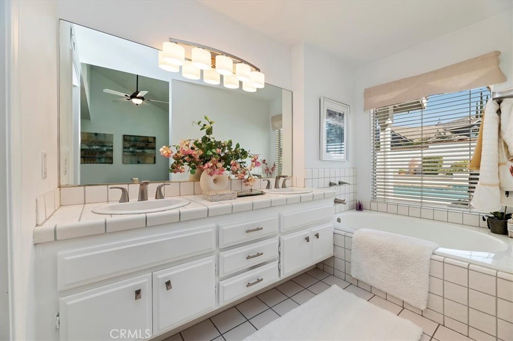 43966 Highlander Drive Temecula, CA 92592 - Photo 16 of 33 a bathroom with a double vanity sink a large mirror a bathtub and next to a window
