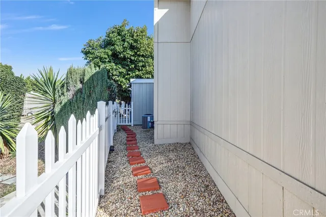 a view of a pathway of a white building with wooden fence