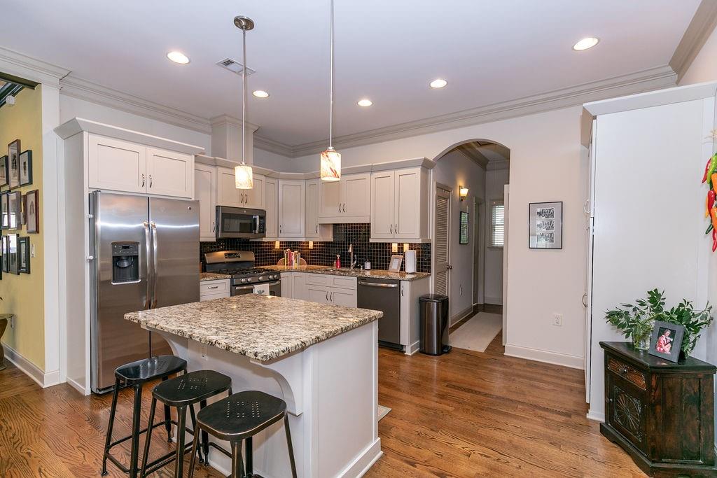 1084 Sanders Avenue Southeast, Unit A Atlanta, GA 30316 - Photo 8 of 44 a kitchen with stainless steel appliances kitchen island granite countertop a refrigerator a stove a sink a dining table and chairs with wooden floor