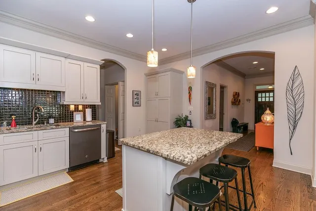a kitchen with granite countertop kitchen island stainless steel appliances a stove refrigerator dining table and chairs