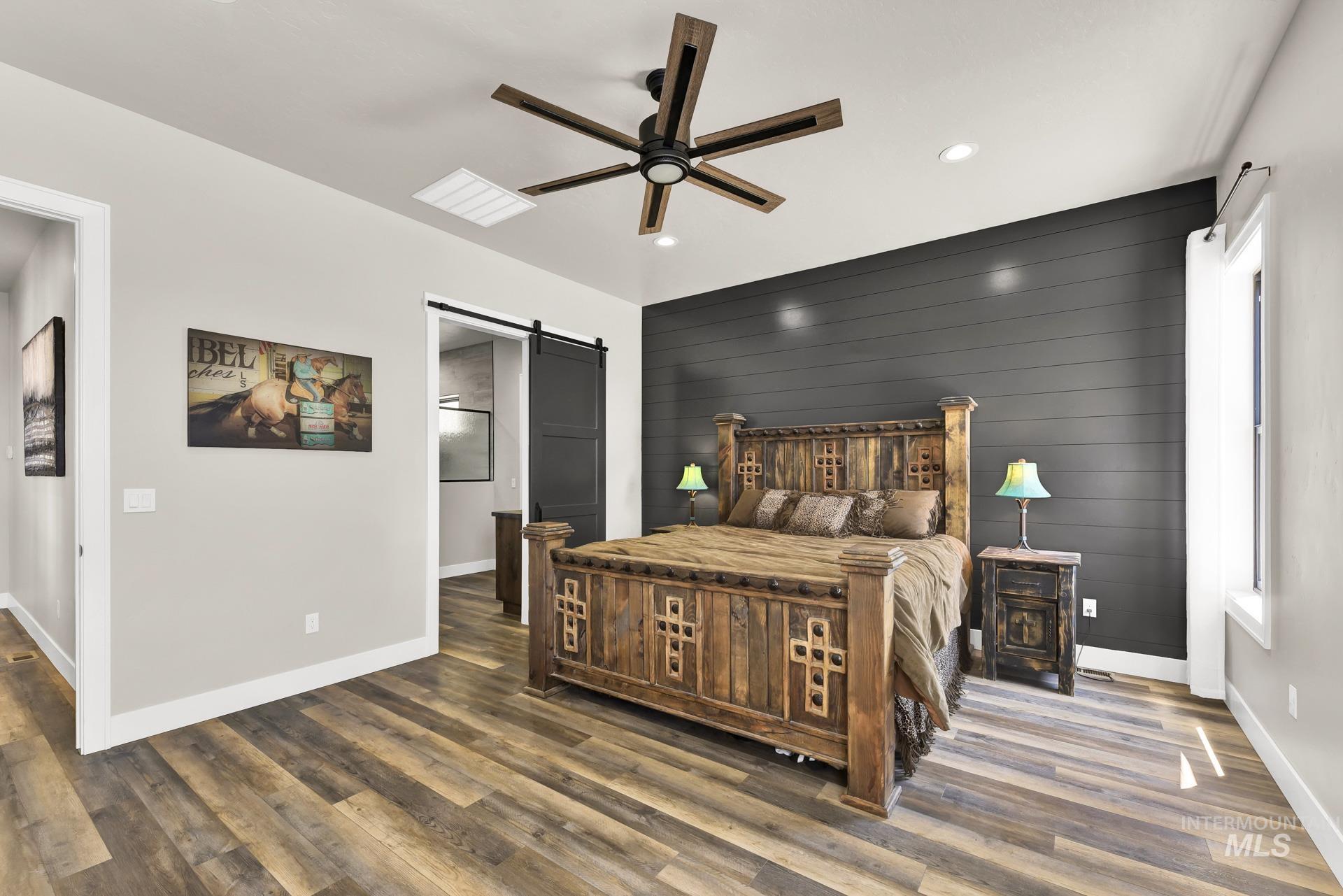 27114 Lower Pleasant Ridge Road Wilder, ID 83676 - Photo 16 of 50 Bedroom featuring a barn door, wooden walls, wood finished floors, ceiling fan, and recessed lighting