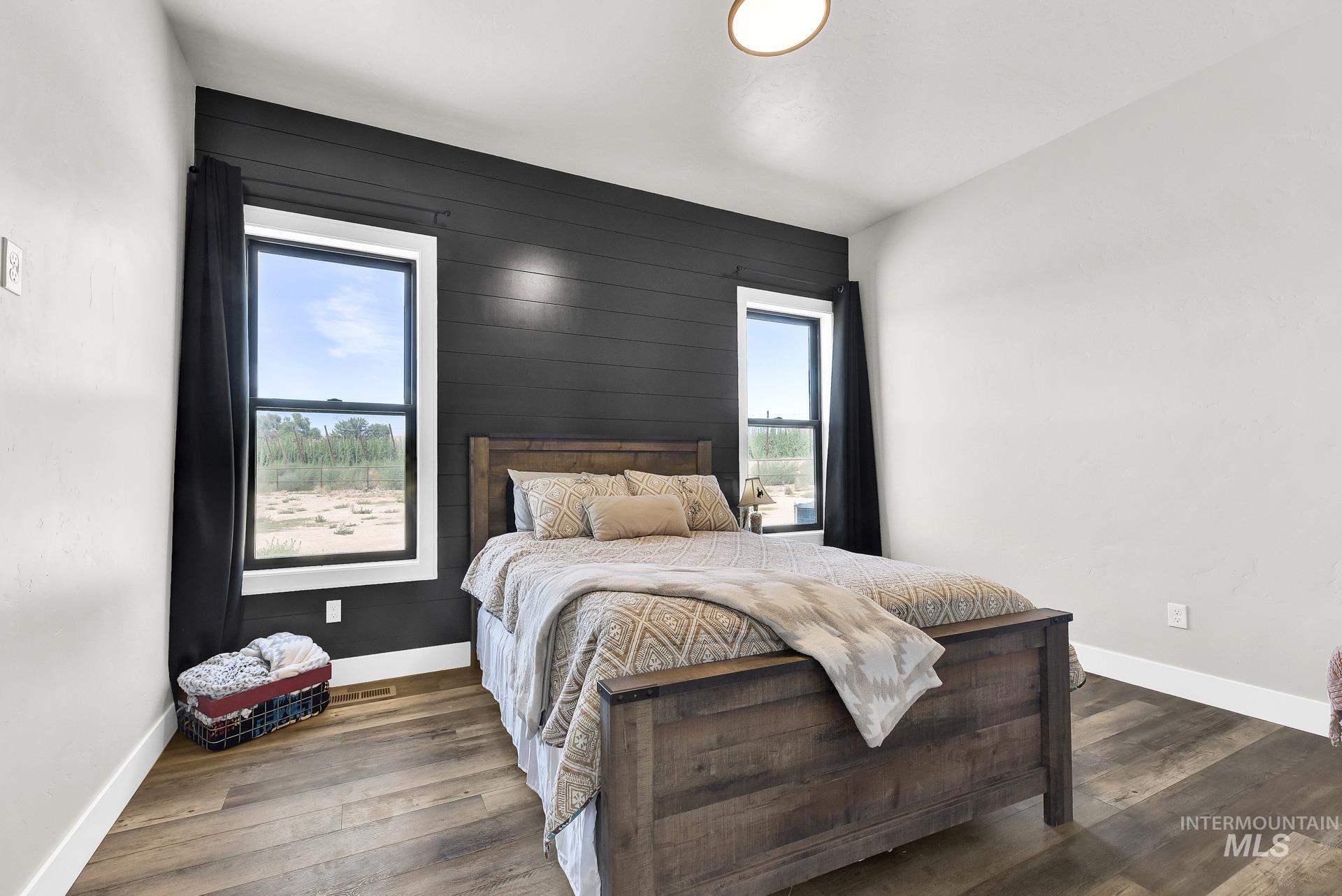 27114 Lower Pleasant Ridge Road Wilder, ID 83676 - Photo 20 of 50 Bedroom with multiple windows, wood walls, and wood finished floors