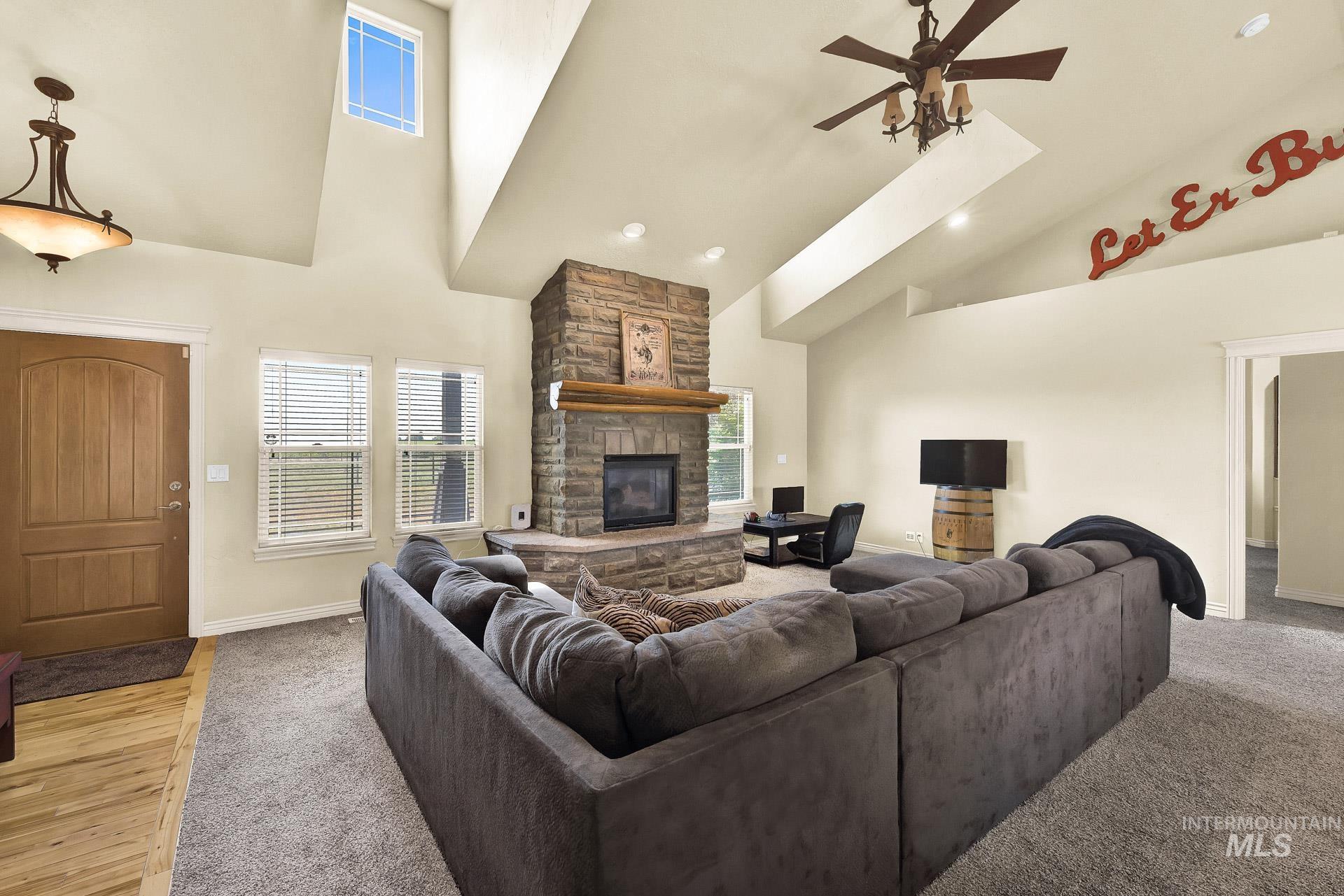 27114 Lower Pleasant Ridge Road Wilder, ID 83676 - Photo 32 of 50 Living room featuring a stone fireplace, high vaulted ceiling, a ceiling fan, recessed lighting, and light colored carpet