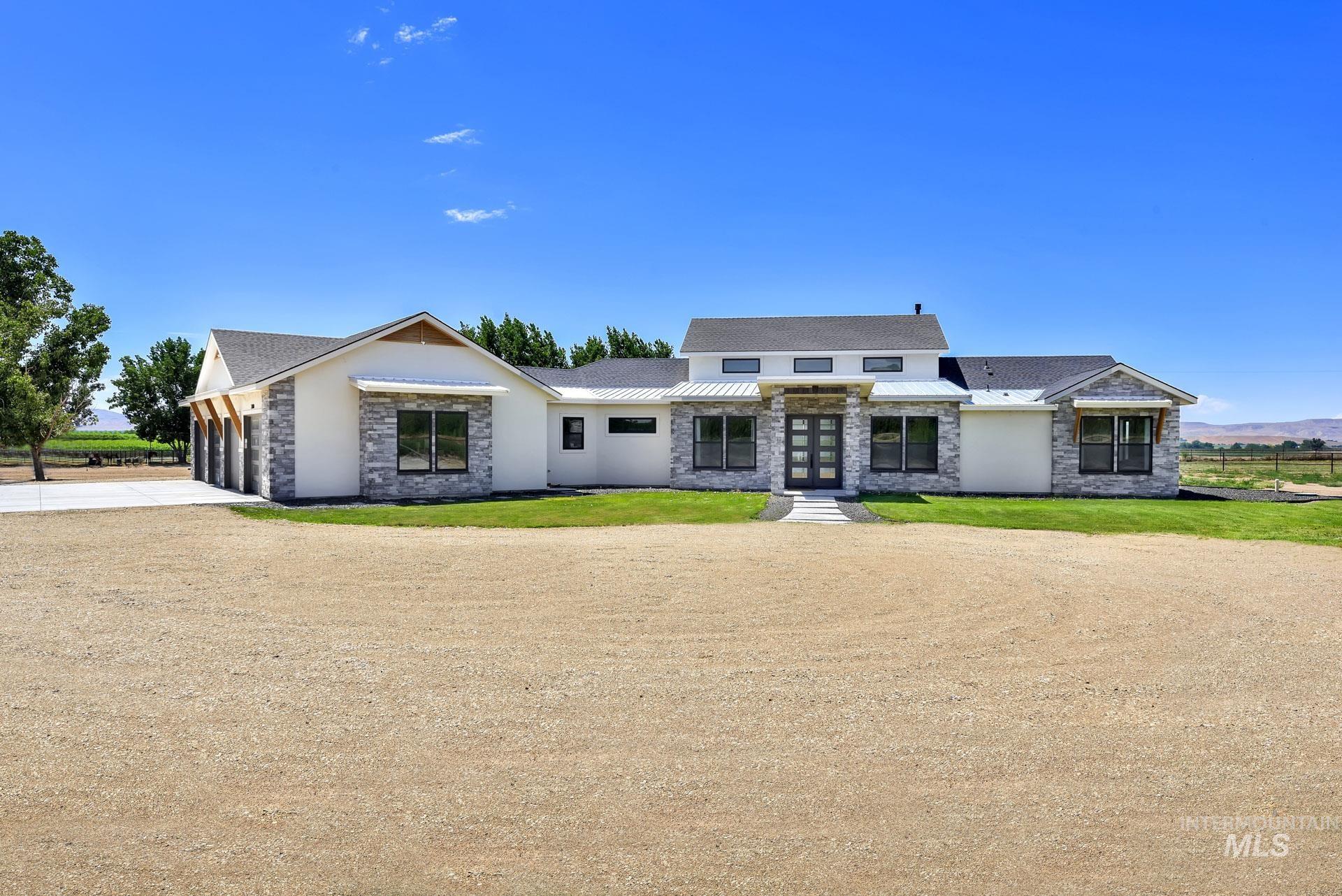 27114 Lower Pleasant Ridge Road Wilder, ID 83676 - Photo 6 of 50 View of front of home featuring stone siding, driveway, a garage, and a front lawn