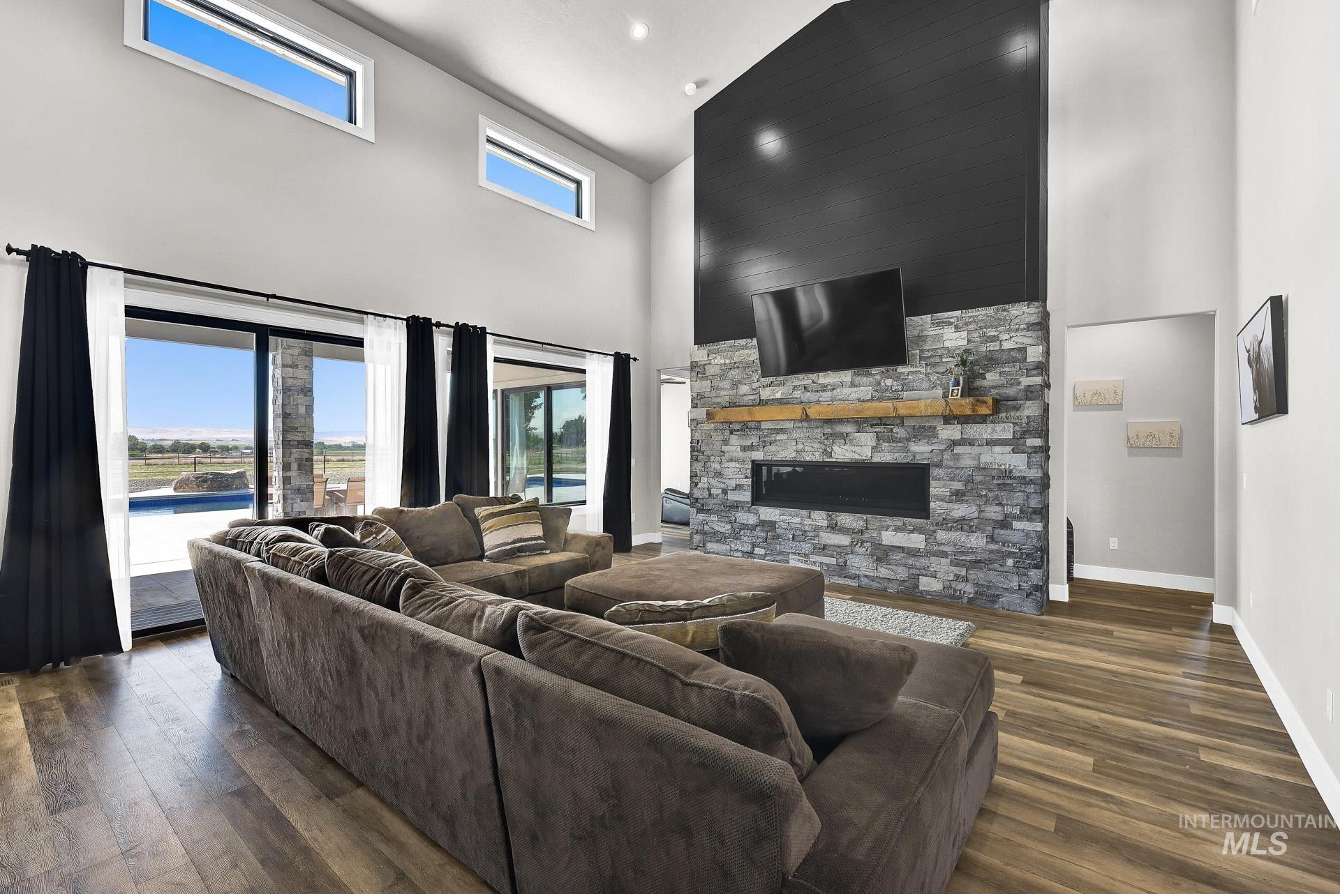 27114 Lower Pleasant Ridge Road Wilder, ID 83676 - Photo 10 of 50 Living area with wood finished floors, a towering ceiling, a stone fireplace, and recessed lighting