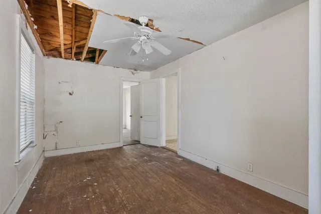 an empty room with windows and ceiling fan