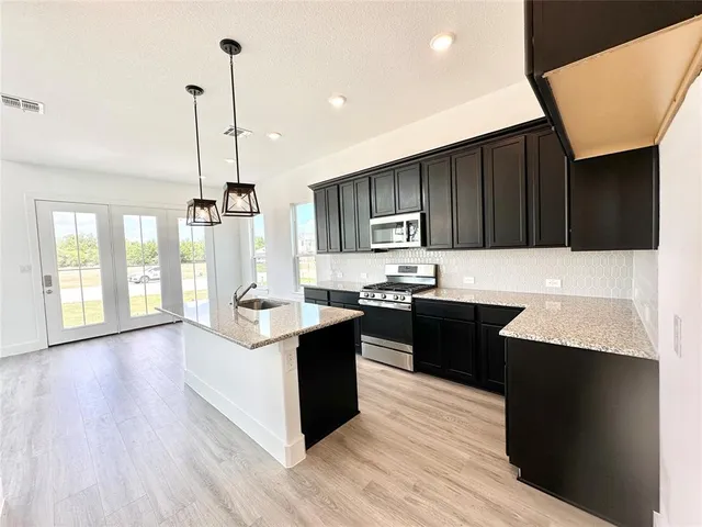 a kitchen with granite countertop a stove and a wooden floors