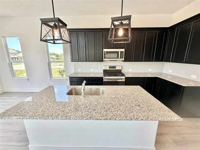 a kitchen with kitchen island granite countertop a sink a stove and a wooden floors