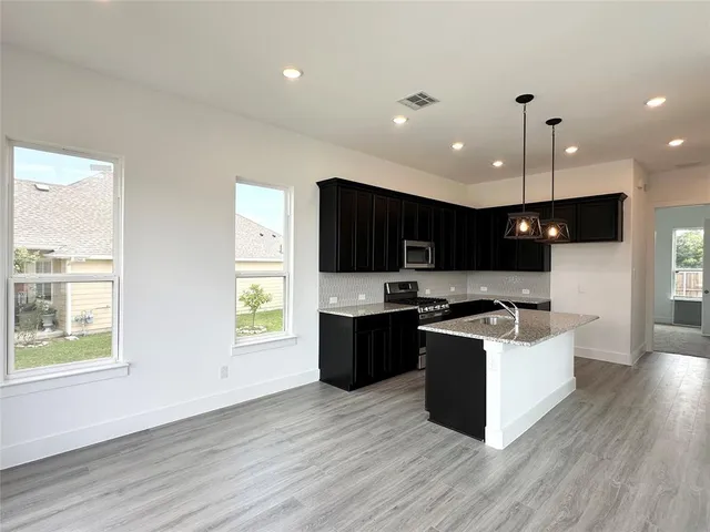 a kitchen with stainless steel appliances kitchen island wooden floors cabinets and wooden floor