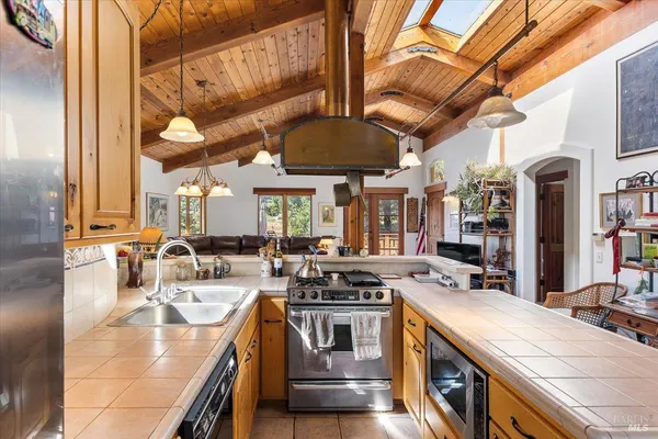a kitchen with stainless steel appliances granite countertop a sink a stove and a wooden floors