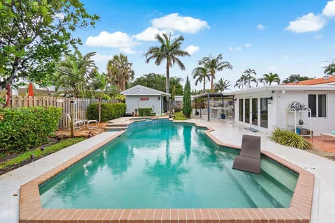 a view of a house with pool lawn chairs under an umbrella