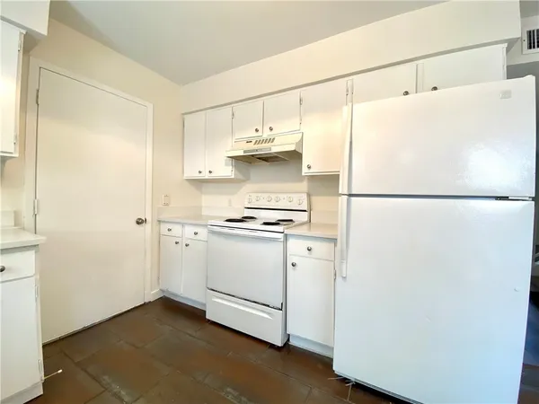 a white refrigerator freezer and a stove sitting inside of a kitchen