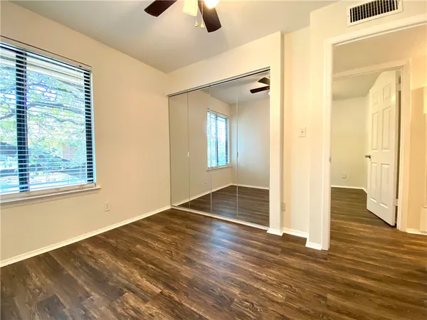 a view of empty room with wooden floor and fan