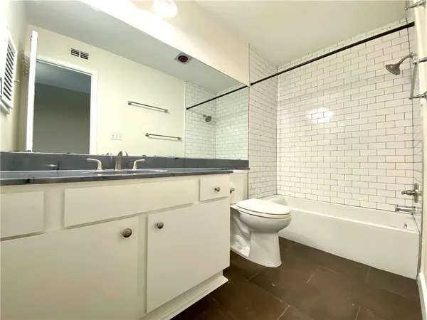 a bathroom with a granite countertop sink a toilet and shower