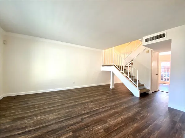 a view of an empty room with wooden floor and stairs