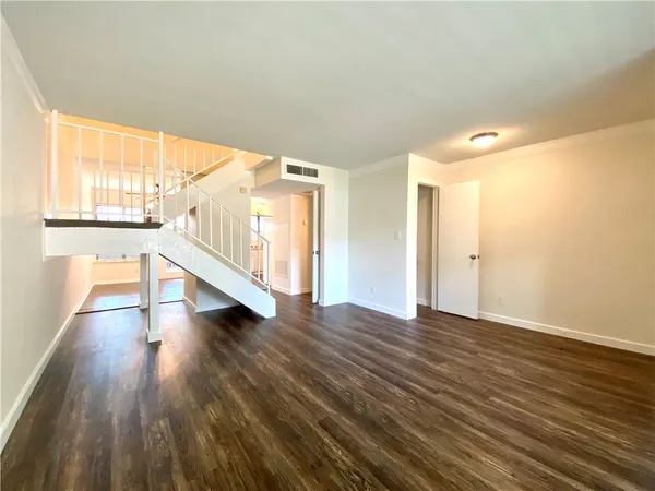 a view of an empty room with wooden floor and windows