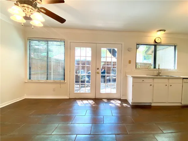 a view of an empty room with a window and kitchen view