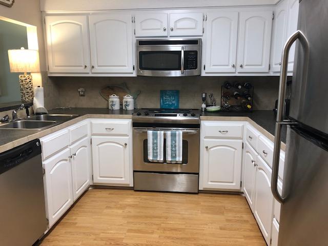 63 Sandy Lane, Unit 102 Santa Rosa Beach, FL 32459 - Photo 14 of 26 a kitchen with granite countertop a stove top oven microwave and cabinets