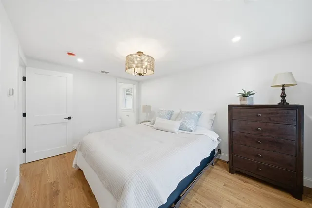 a bedroom with a bed and a lamp on dresser