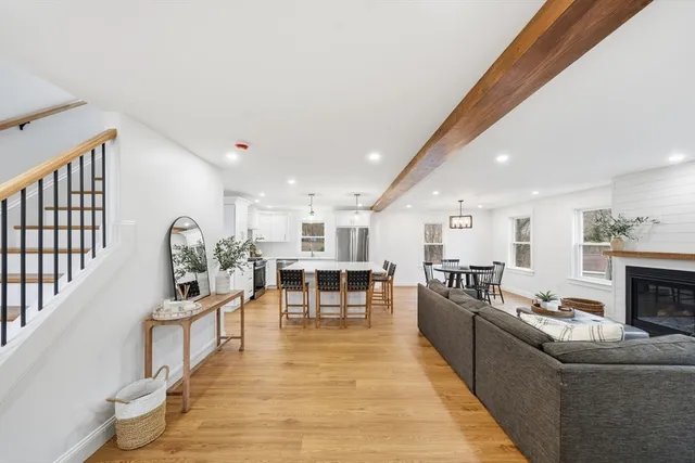 a living room with stainless steel appliances furniture a rug and a view of kitchen