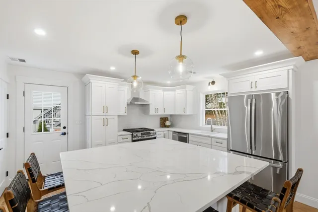 a kitchen with stainless steel appliances a refrigerator a sink dishwasher a stove and a dining table with wooden floor