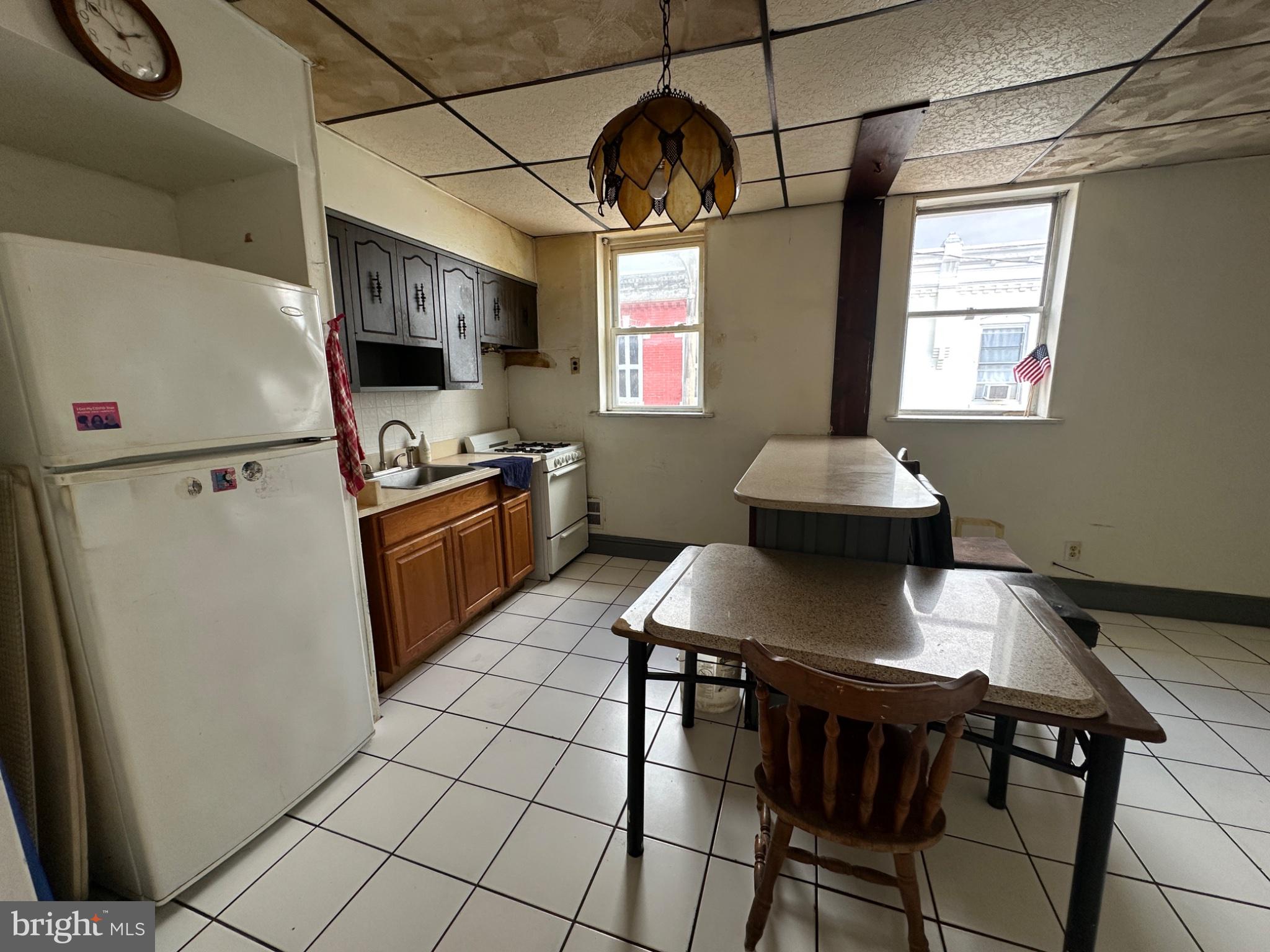 715 West Ritner Street Philadelphia, PA 19148 - Photo 5 of 19 a kitchen with stainless steel appliances granite countertop a stove a refrigerator a sink a dining table and chairs with wooden floor