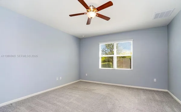 an empty room with a window and a fan