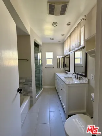 a large bathroom with a large mirror vanity and toilet