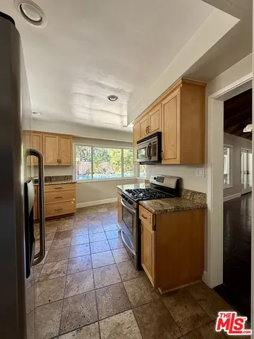 a kitchen with granite countertop a refrigerator and a stove top oven