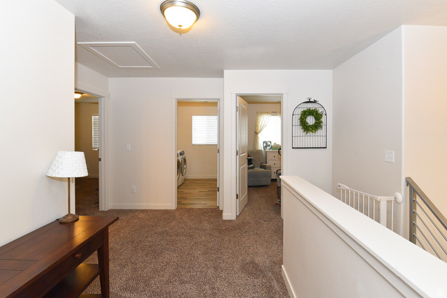 1632 North Apache Road Saratoga Springs, UT 84045 - Photo 20 of 28 Upper-level hallway featuring plush carpeting, a ceiling-mounted light fixture, white interior doors, and a staircase with a horizontal metal railing