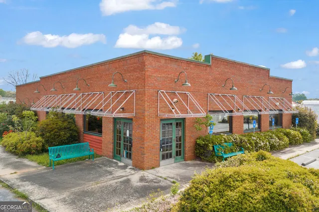 a view of a white house with a yard plants and large tree