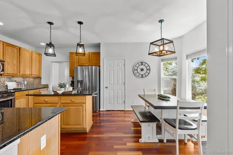 a kitchen with stainless steel appliances granite countertop a stove a sink dishwasher and a wooden floor
