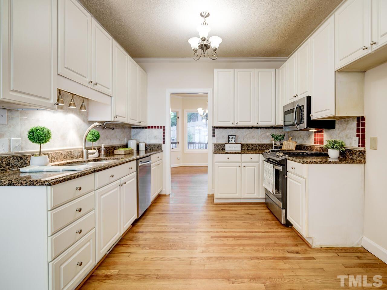 4121 Starboard Court Raleigh, NC 27613 - Photo 20 of 45 a kitchen with granite countertop white cabinets and white appliances