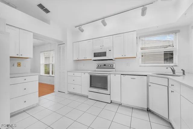 a kitchen with white cabinets and white appliances