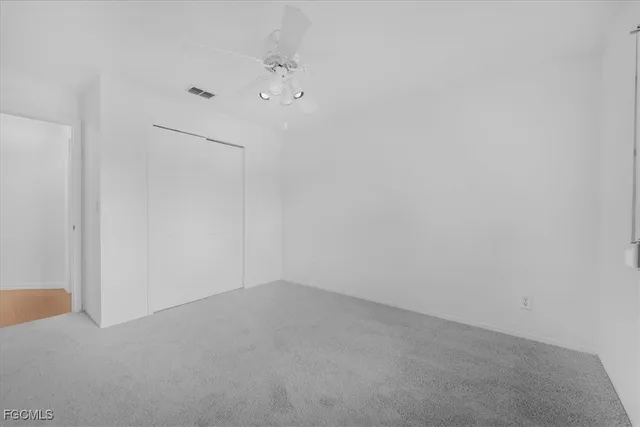 an empty room with a ceiling fan and closet area