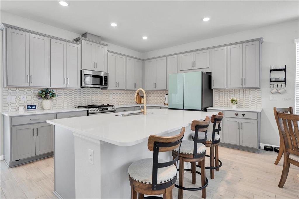 13639 Rangeland Boulevard Odessa, FL 33556 - Photo 9 of 63 a kitchen with stainless steel appliances a stove a sink a microwave a refrigerator and white cabinets