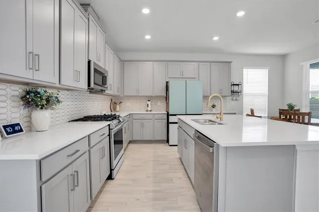 a kitchen with a dining table chairs appliances and cabinets