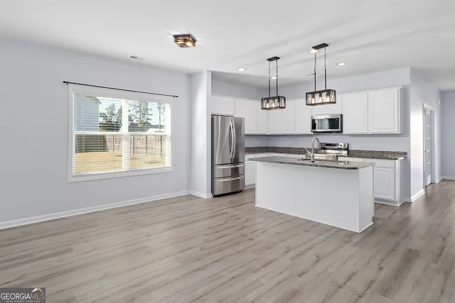 a kitchen with stainless steel appliances granite countertop a stove a refrigerator and a wooden floors