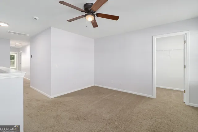 an empty room with closet and a ceiling fan