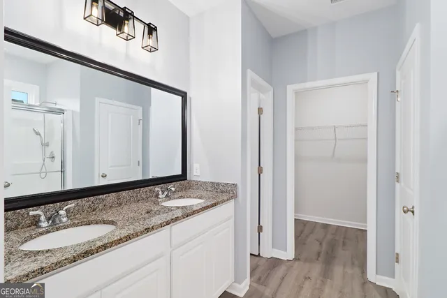 a bathroom with a granite countertop double vanity sink and mirror