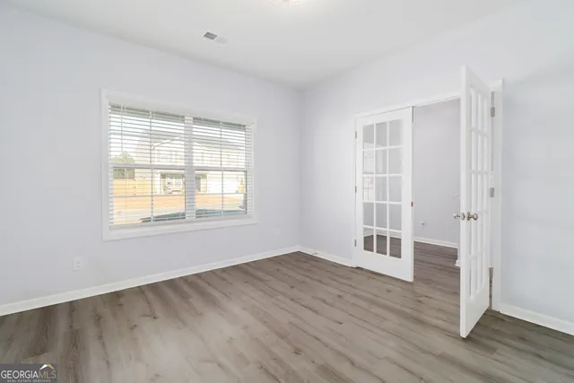 an empty room with wooden floor and windows